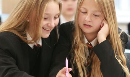 two students smiling and working together in class